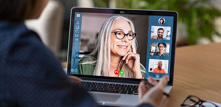 person looking at laptop screen showing conference call with four other people