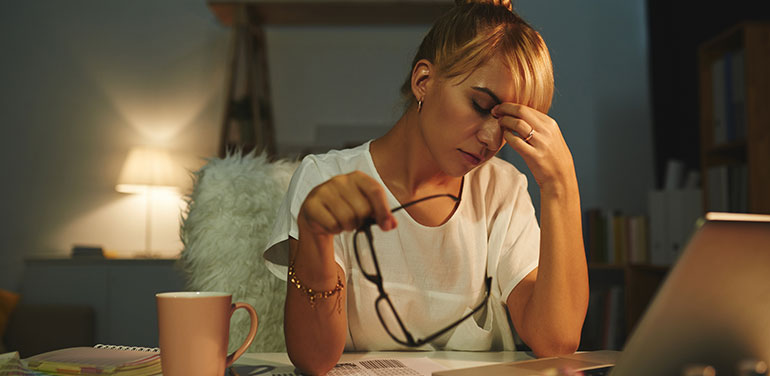 Woman with her hand on her head, looking stressed sitting at her desk