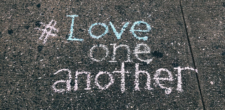 words Love one another written in chalk on the pavement