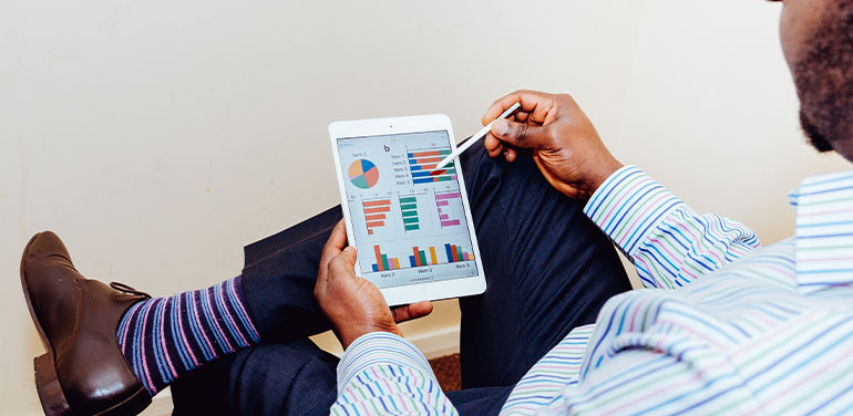 man sitting down looking at graphs on an ipad