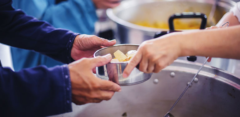 handing over food in a soup kitchen, close up of hands on a bowl