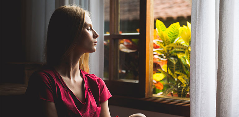 young woman with her eyes closed sitting in a window