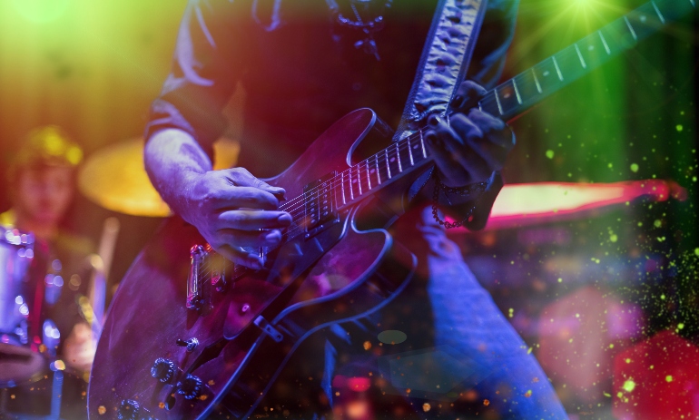 A man is playing guitar on stage, close-up.