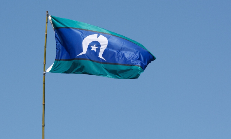 Torres Strait Islander Flag wave against blue sky in Australia. The Torres Strait Islander Flag represents Torres Strait Islander people.