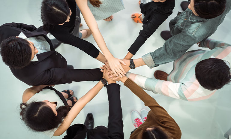 aerial view of people standing in a circle hands in the middle