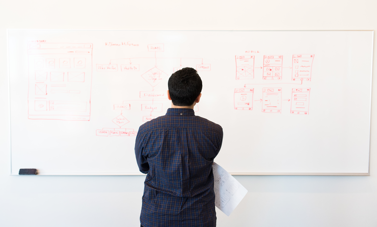 man looking at drawings on a whiteboard