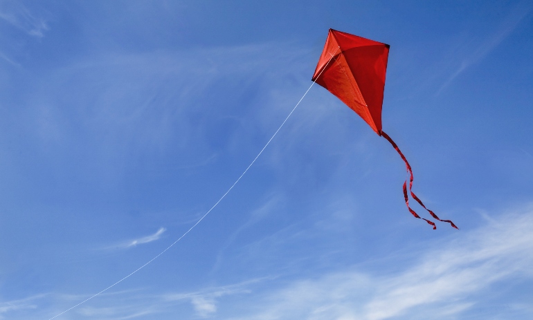 A red kite flying against a blue sky.