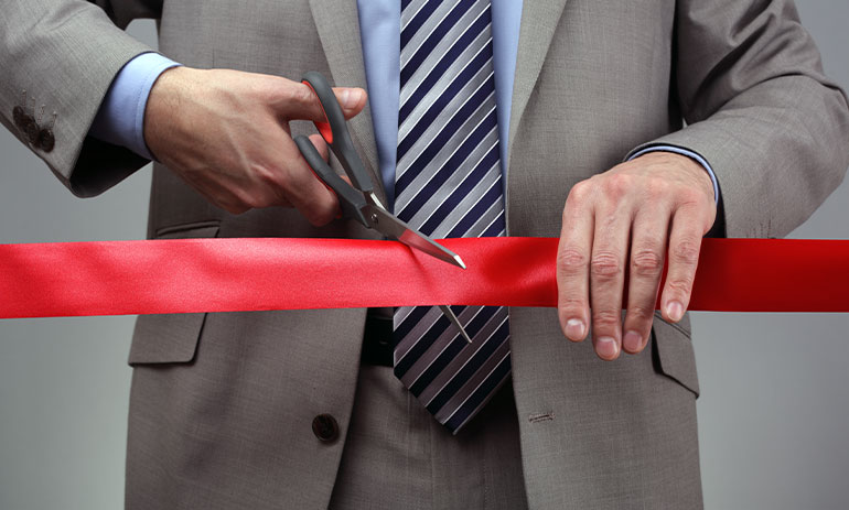 map cutting a red piece of red tape with scissors