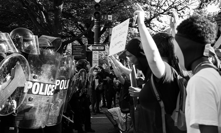 Photo of protesters standing in front of a line of police at a Black Lives Matter demonstration in Washington DC.