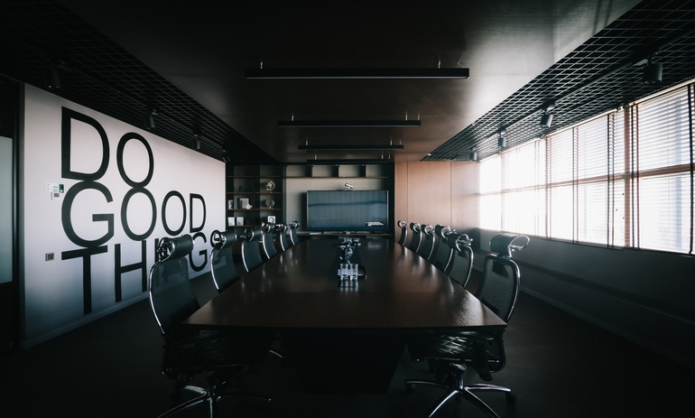 empty board room with table in the middle and the words "Do Good Things" on the left wall