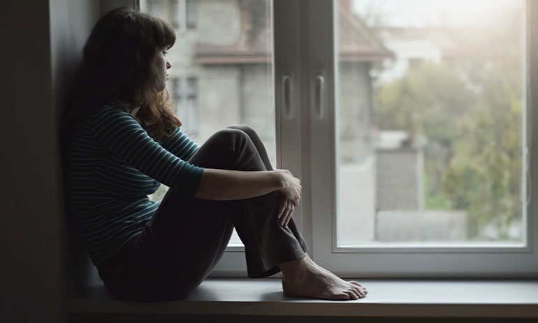 woman sitting in window looking outside