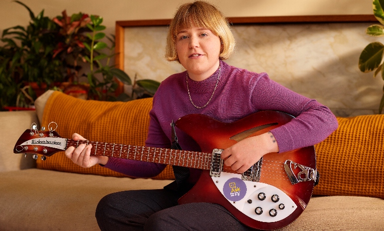 Woman sitting down with a guitar