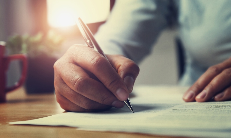 hand of woman holding pen with writing on paper report in office