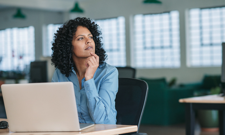 Woman thinking while sitting at desk on laptop