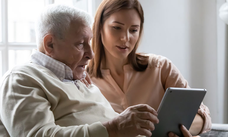 woman teaching older man how to use ipad