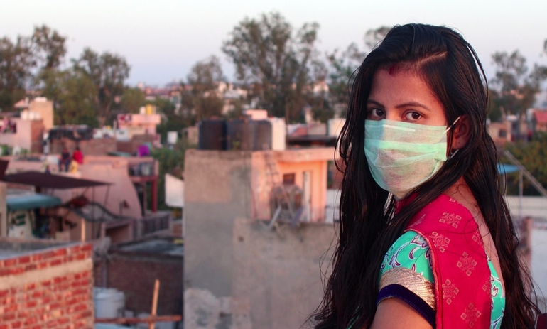 girl with face mask looking over her shoulder at the camera