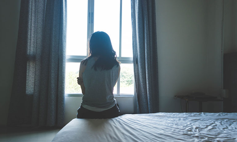 person sitting on bed looking out window