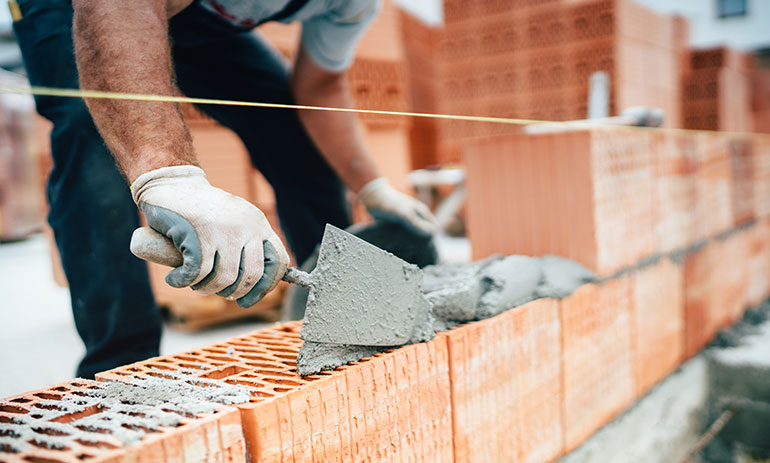 close up man laying bricks to build house