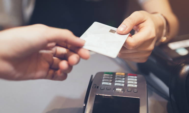 Close up of hand using credit card swiping machine to pay.