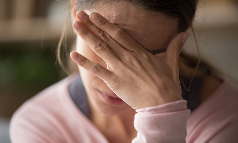 woman wearing pink top with her hand covering her face