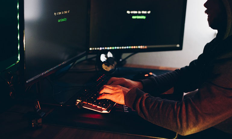 man typing on a computer in the dark.