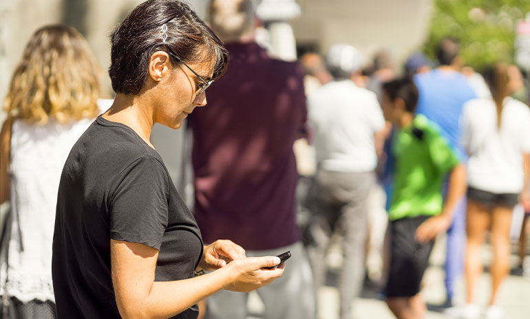 women on her phone with people queuing in front of her