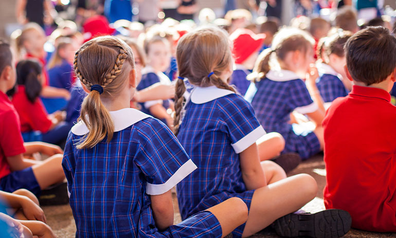 kids sitting on the floor in school wearing uniforms