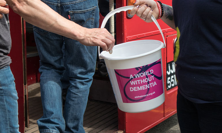 Hand putting a coin donation into a charity collection bucket