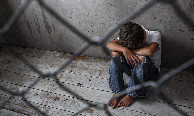 child sits behind bars