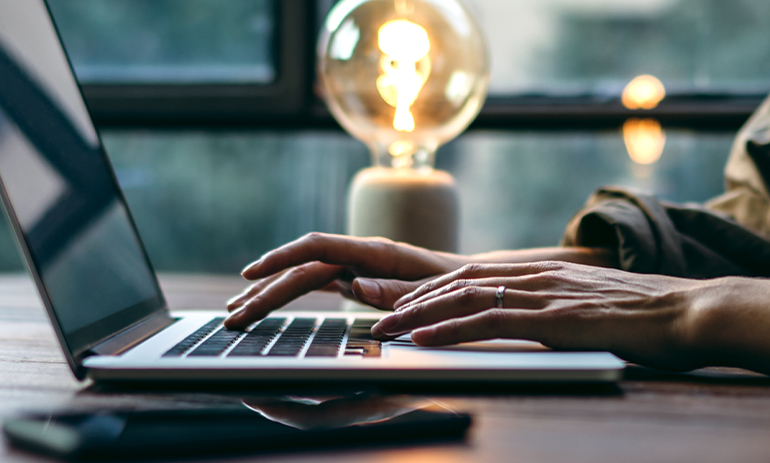 person on laptop with lightbulb in the background