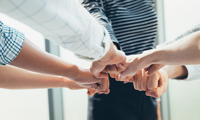 group all putting their hands in the middle of a circle