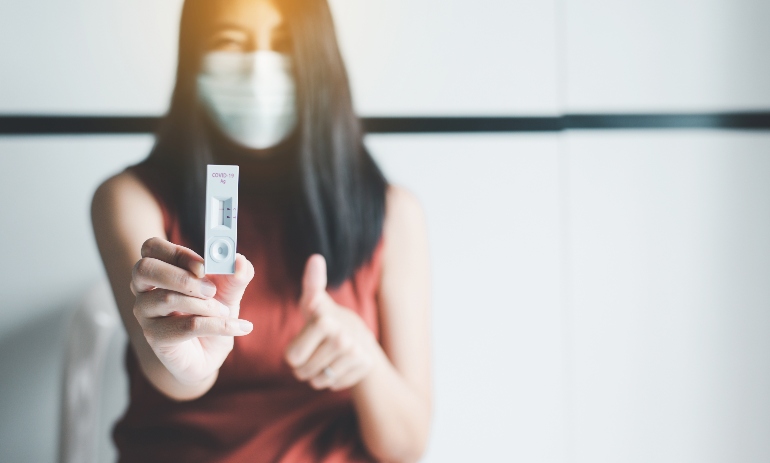 Patient woman showing result a covid-19 self test rapid antigen testing kit at home