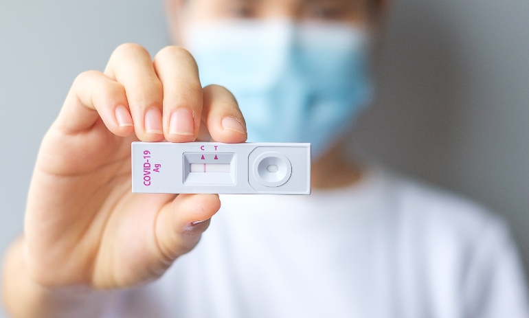 woman holding Rapid Antigen Test kit