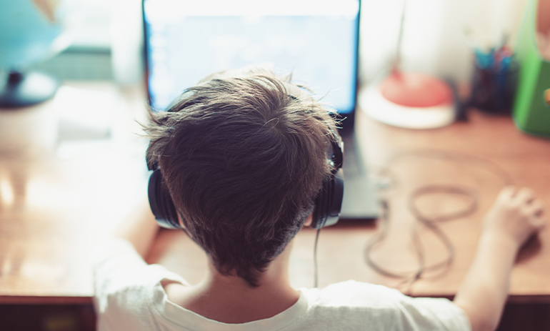 back of the head of a child looking at a laptop