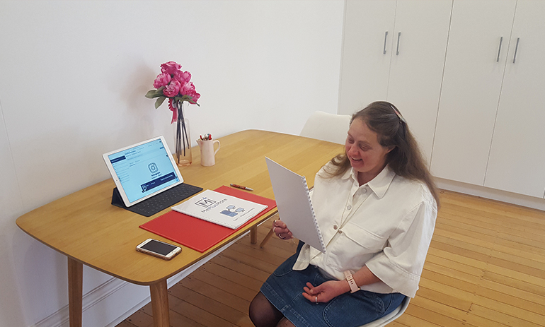 A lady sits at her desk reading a workbook