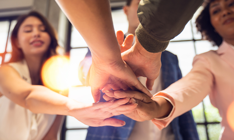 group of people putting hands into middle of circle