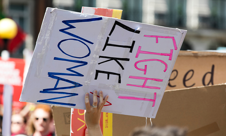 Hands hold a sign reading fight like a woman