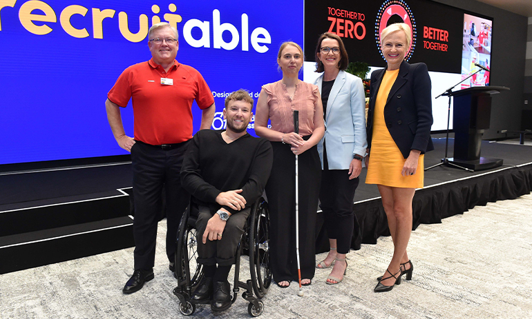 A group of people stand behind Dylan Alcott