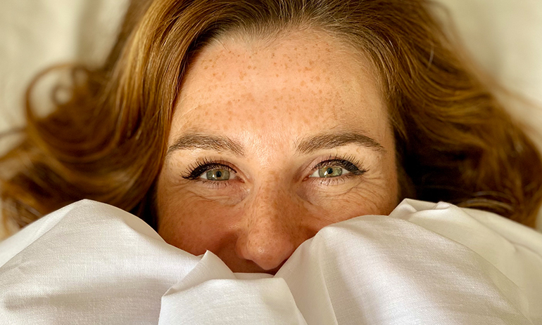 lady peeps out under a white sheet