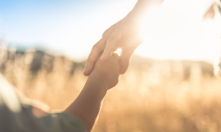 adult holding child's hand