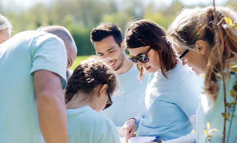 group of volunteers wearing blue t-shirts standing around looking at a clip board