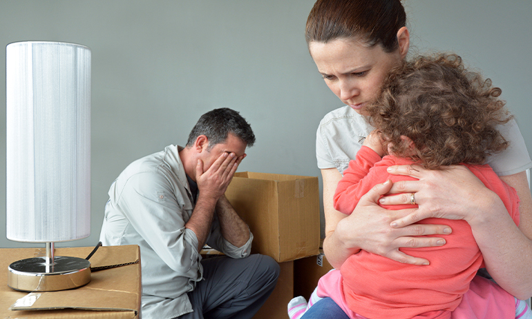 family looking upset surrounded by cardboard boxes