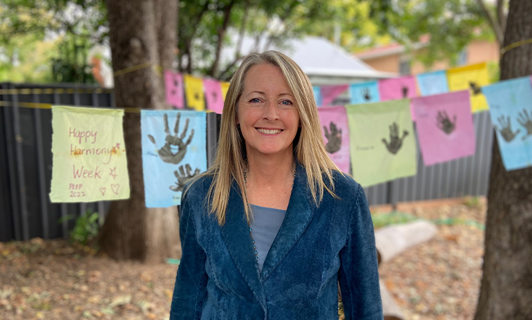 Rosei Koop standing outside with children's pictures hanging on a line behind her