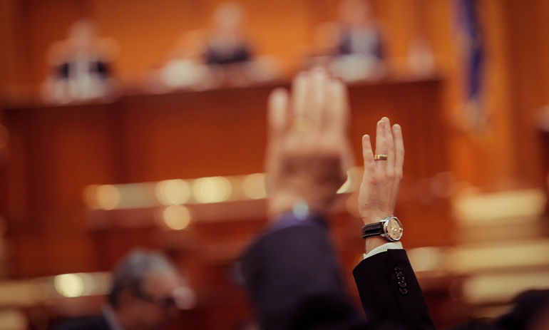 blurry photo of hands being raised as MPs vote