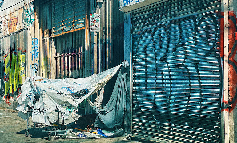 A shelter in an industrial-looking area covered in graffiti