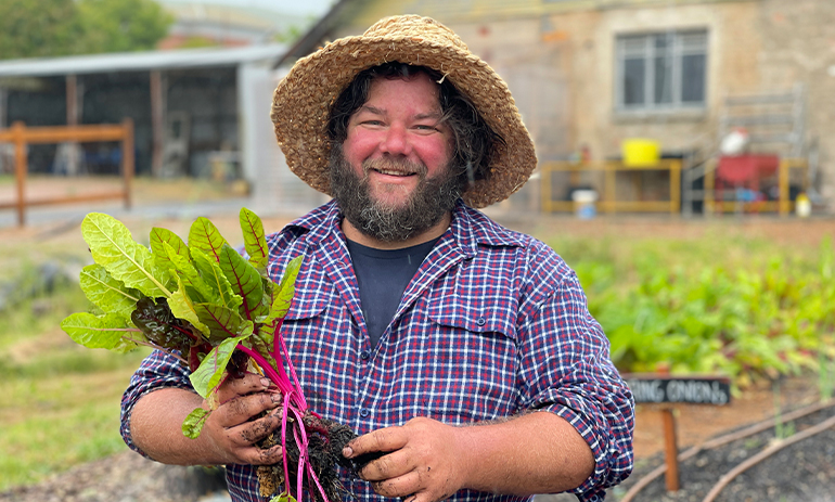 Josh Collings standing in a garden holding greens