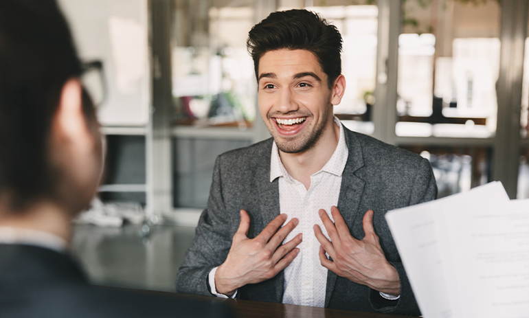 Man smiling and point to himself in a job interview