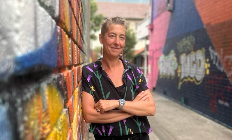 Jana Favero standing against a wall with graffiti on it