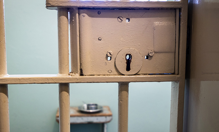 Looking through the bars of a jail cell into the cell