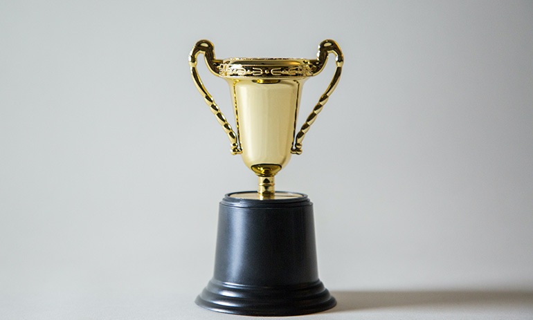 A golden trophy against a neutral grey background.